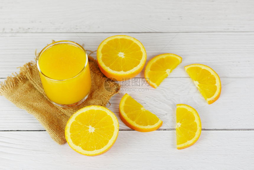玻璃中的橙汁和木制桌上的新鲜橙子水果片图片