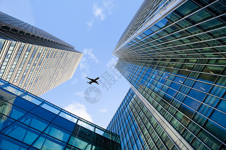 一架飞机在高楼大厦上空飞行图片
