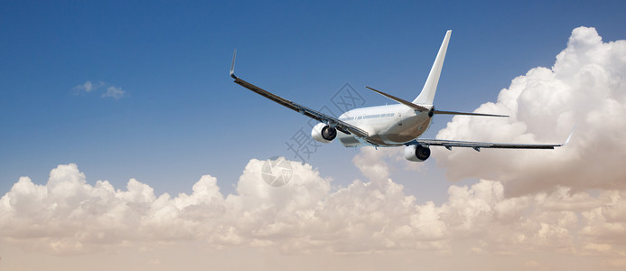 白色客机飞越蓝天白云上空图片
