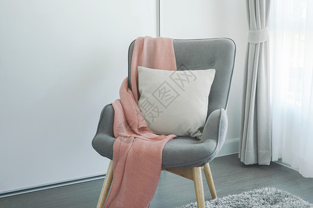 在起居室拐角处的灰臂椅上粉丝围巾和蜜蜂枕头背景图片