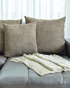 现代客厅内灰色皮革沙发和棕纹身枕头图片