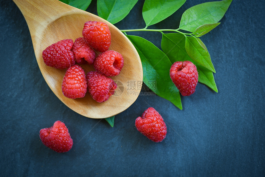 木勺上新鲜的草莓红色成熟的草莓果和深底绿叶图片