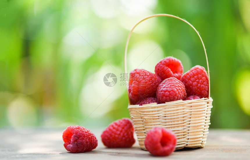篮子里新鲜的草莓以木制和自然绿色模糊背景关闭红成熟的草莓果图片