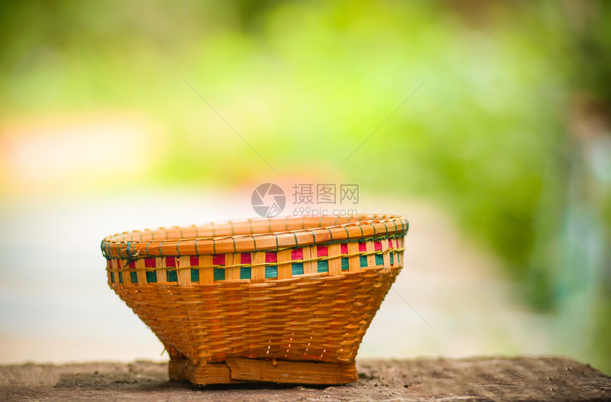 在有夏季自然绿色和黄背景的旧木上编织竹篮子图片