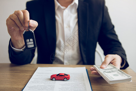 汽车销售人员拿着汽车钥匙向客户介绍保险概念图片