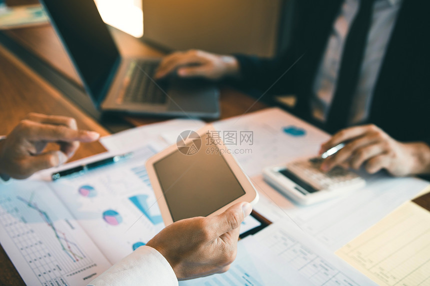 使用平板片分析公司财务预算报告图表和成本计算工作进度和未来办公室规划图片