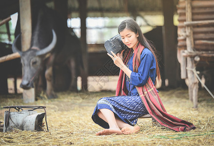 奶牛声音素材亚洲农业女民在村描绘美丽的年轻女孩快乐笑和听水牛农场旧收音机穿衣部落生活背景