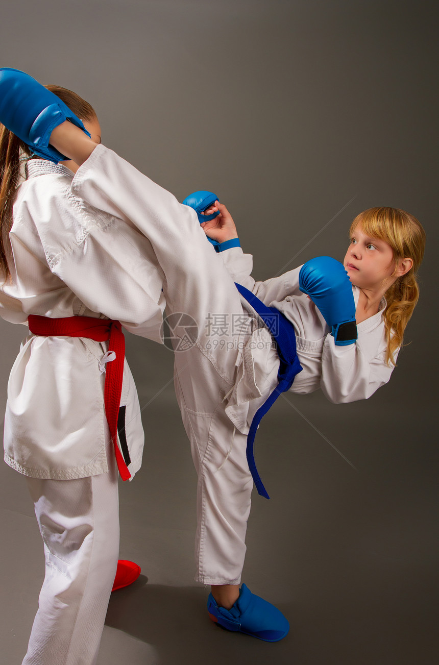 空手道在红色的白和服中与两个小女孩战斗图片