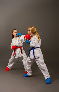 空手道在红色的白和服中与两个小女孩战斗图片