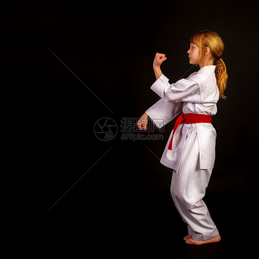 身穿运动和服的小女孩红腰带在黑暗背景下卡塔进行操练图片