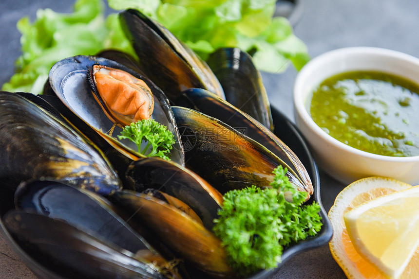 食用含草药柠檬和黑板底新鲜海贝壳鱼在碗上餐室贝壳食品中的辣酱加图片