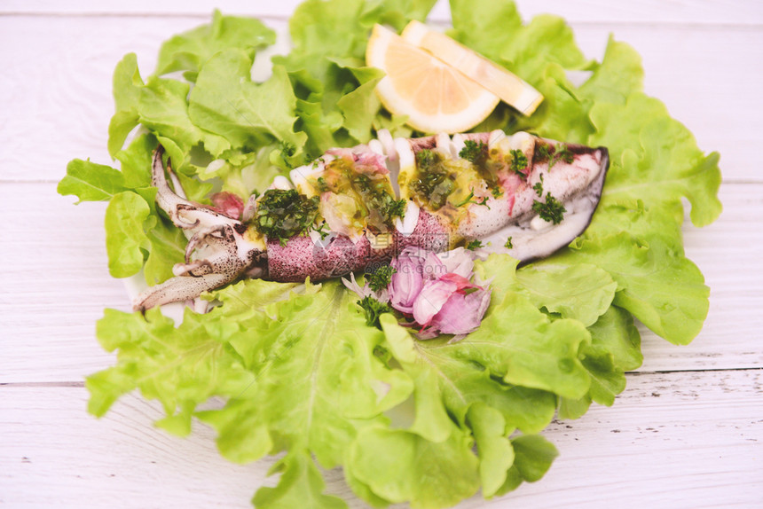 蔬菜上加酱汁的鱿鱼在海鲜餐厅煮饭图片