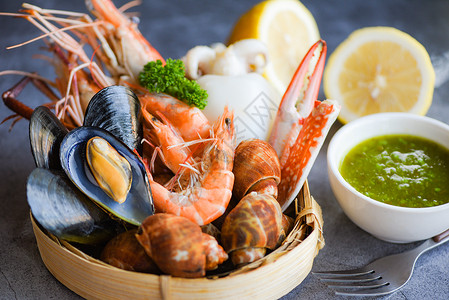 盘面黑石背景的比伦贝壳螃蟹和海鲜酱柠檬烹饪蒸汽食品为海鲜自助餐提供的概念背景图片