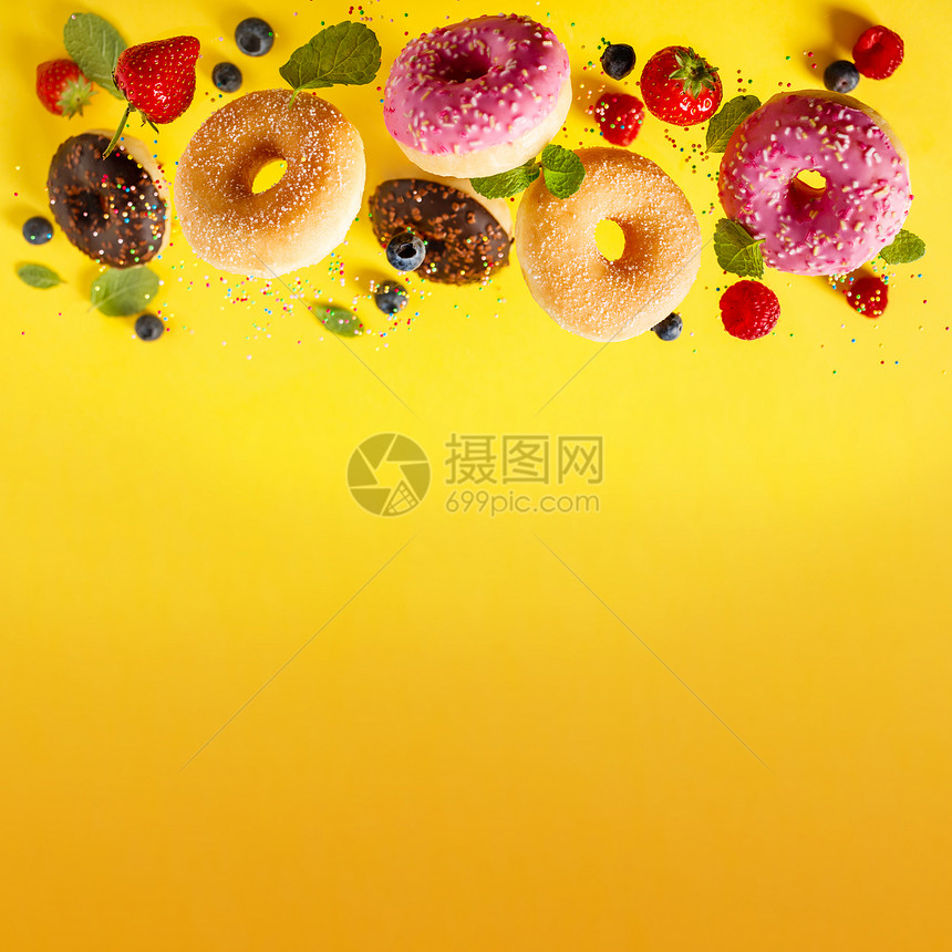 各种装饰的甜圈喷洒着糖和浆果在摇摆不定的背景中落下甜圈在摇摆或飞动中落下图片