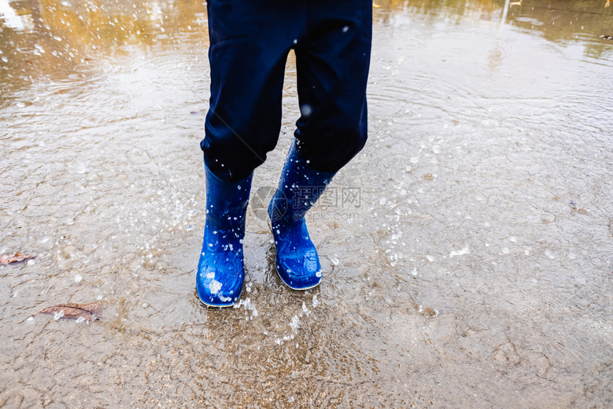 男孩在雨天过后街上跳水图片