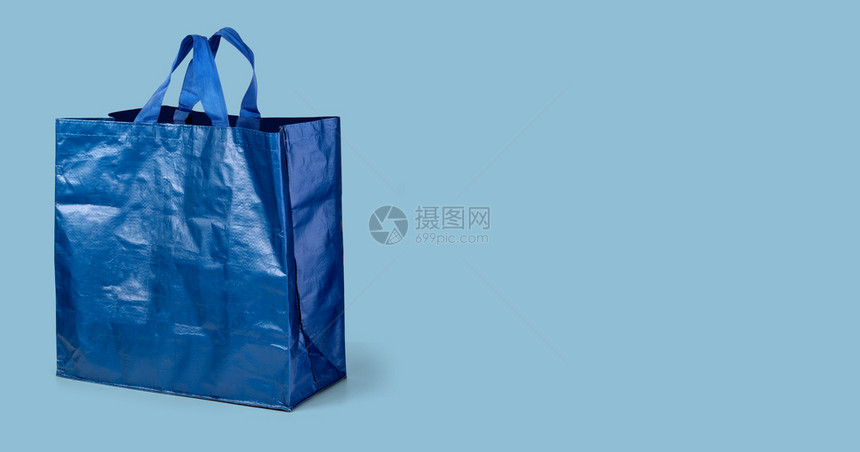 蓝色购物袋在浅蓝色背景和剪路上被孤立图片