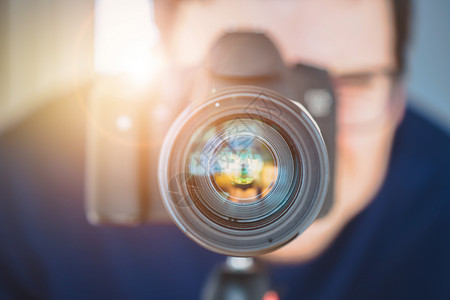 摄影师站在一个专业摄影机的后面上有三脚架的远光镜头太阳束背景图片