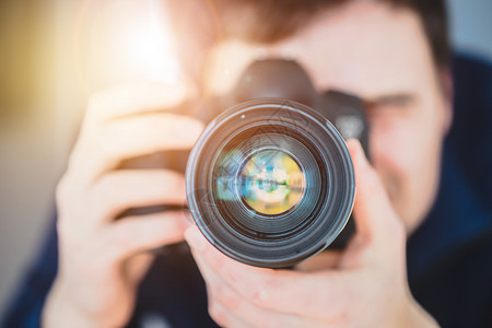 摄影师站在一个专业摄影机的后面上有三脚架的远光镜头太阳束背景图片