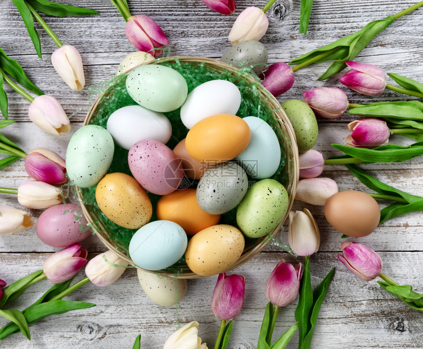 复活节快乐概念满一篮彩蛋和白生锈木上春花的篮子图片