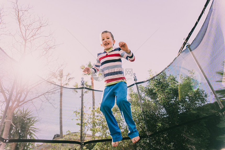 5岁的男孩跳上踏板在家庭后院运动享受春天快乐和生活方式的姿态图片