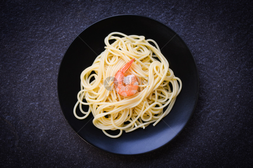 意大利面条和虾在黑背景意大利食品和菜单概念板上服务图片