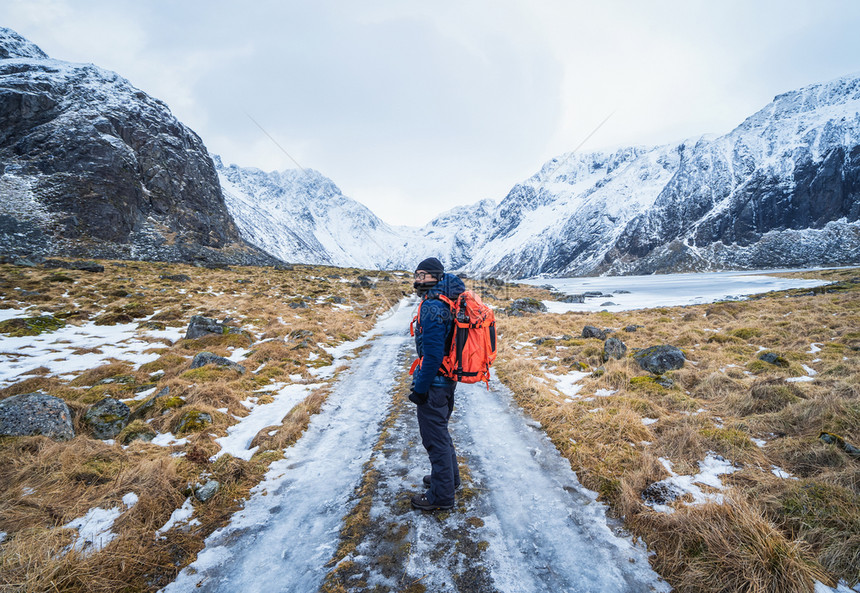 一位亚洲游客背着包在冰川上旅行挪威欧洲洛福登岛冰湖白雪山冬季自然景观旅行徒步和冒险概念图片