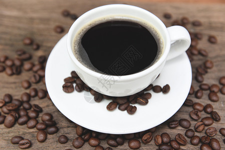 咖啡杯和豆在桌上黑咖啡白杯中的黑咖啡在木制背景上图片