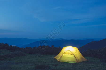 黄色放射星光山上的黄色帐篷夜空下露营背景