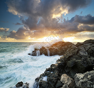 风暴的海景自然构成暴风雨期间的海浪在日落时喷洒到石头上图片