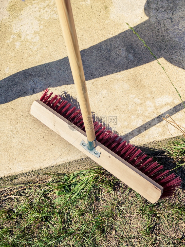 使用大扫帚清洁后院子的人家务义概念图片
