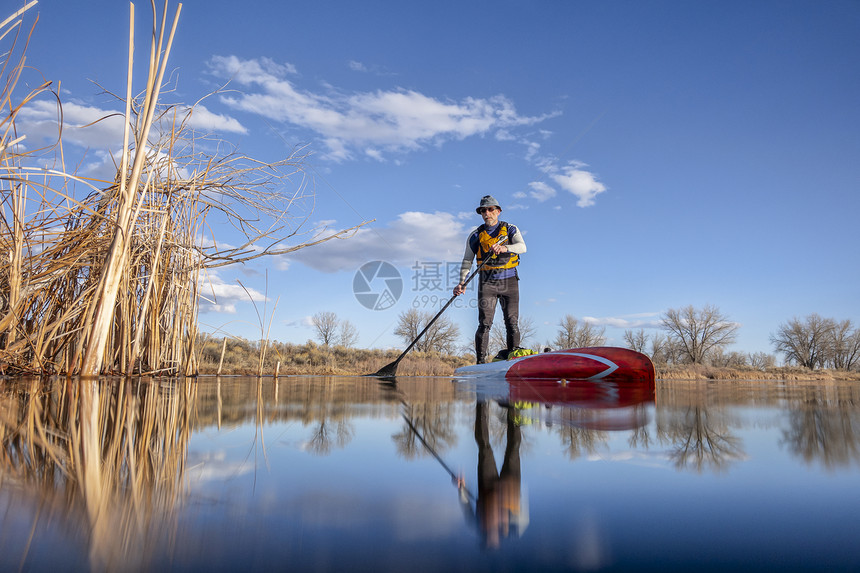 中年男子在湖上站立划船图片
