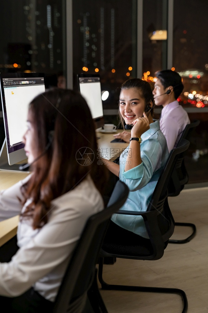 亚洲青年成人信任操作员同事团队有耳机夜间在呼叫中心工作为客户服务和技术支助使用晚夜辛勤工作24Hr7天概念图片