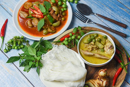 茶饭碗和白盘上的红咖哩泰国菜汤碗上的绿咖喱和白盘上的红咖哩桌边有茶米面背景图片