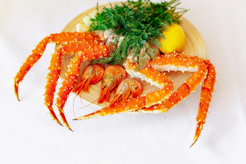 虾螃蟹柠檬和绿色放在盘子上的白色背景图片