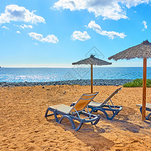 桑迪沙滩带阳伞和沙尾长鱼海边的背景图片