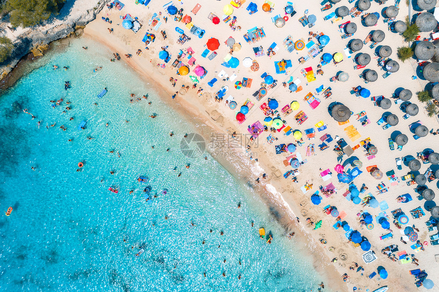 沙滩的空中景象与多彩的雨伞在夏季日落时用透明的蓝水在海滨游泳西班牙巴利阿里群岛马洛卡旅行图片