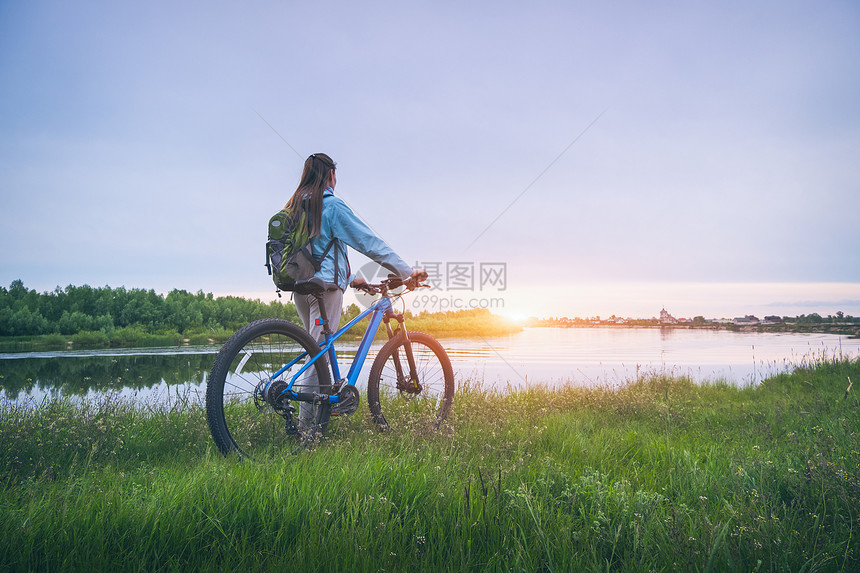 在河边骑自行车的妇女图片