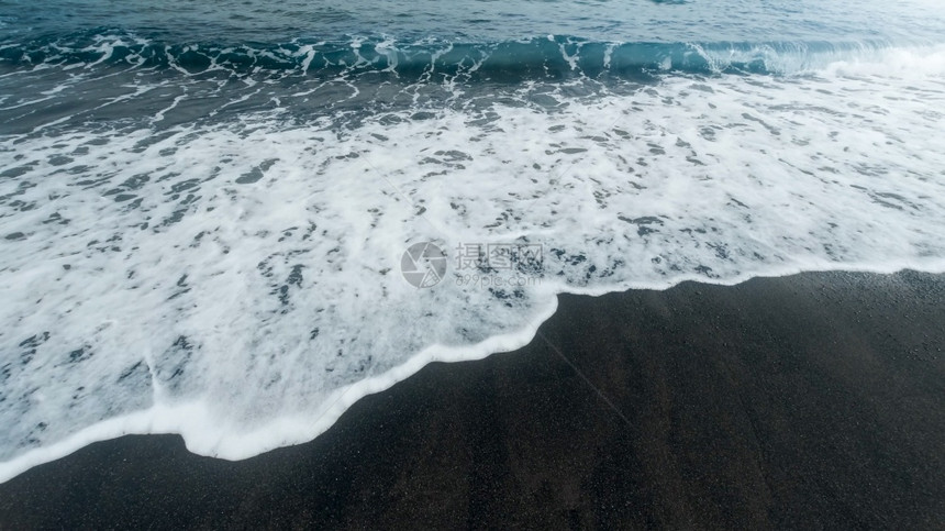 蓝色海浪以黑火山沙子在海滩上滚动和破碎的美丽图像蓝色海浪以黑火山沙子在海滩上滚动和破碎的美丽图像图片