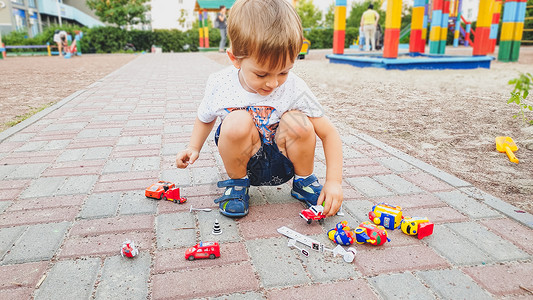 小男孩坐在公园的地上玩玩具车图片