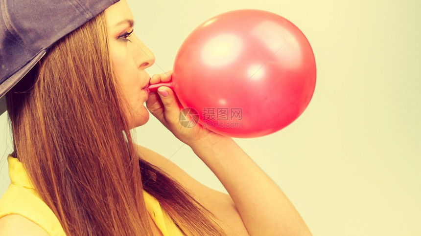 年轻潮流女子准备生日庆典装饰女青少年戴帽子发红气球女青少年充气红球图片