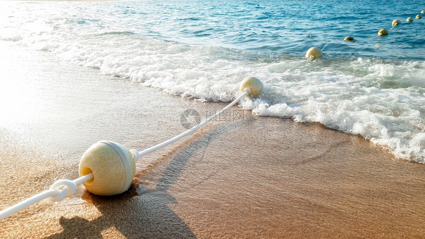 紧贴的漂亮照片显示长的浮标线绳在海上漂浮并紧贴在沙滩上图片