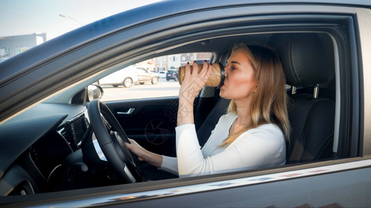 一边开车一边喝咖啡的女司机肖像图片