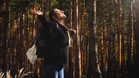 年轻女在森林中穿梭双手伸展享受温暖的太阳光自由与然和谐的概念年轻女在森林中穿梭享受温暖的太阳光自由与然和谐的概念夏天高清图片素材