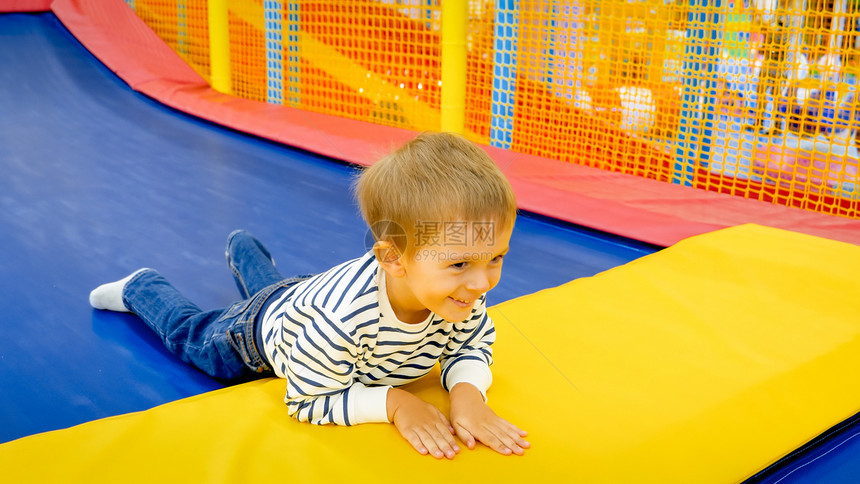 快乐笑的小男孩肖像躺在游乐公园的流浪汉上图片