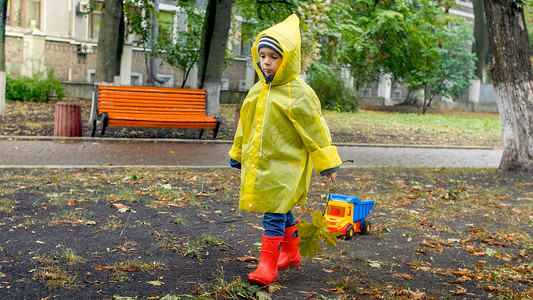 雨桶雨天在公园穿雨衣玩耍的男孩背景