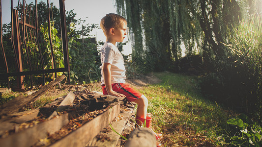 可爱小男孩坐在河岸长椅上生活方式高清图片素材