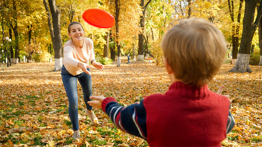 小男孩和他的妈妈在公园里玩飞盘背景图片