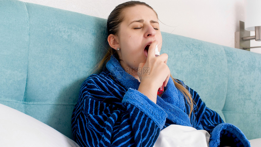 使用Thpat喷雾洒流感的患病妇女肖像图片