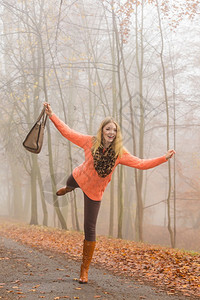 穿着毛衣的快乐年轻女孩穿着毛衣拉包在森林里放松图片