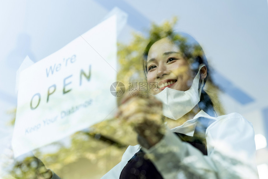 亚洲女服务员为新的普通餐厅设置开放标志和社交距离新的正常餐厅生活方式概念图片